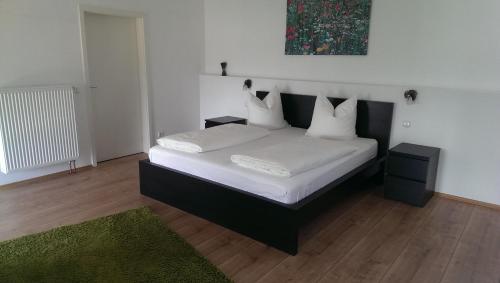 una camera da letto con letto, lenzuola e cuscini bianchi di Zum Rebhang Bed & Breakfast a Oestrich-Winkel
