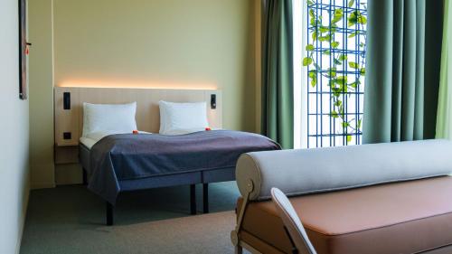a bedroom with a bed and a couch and a window at Citybox Kristiansand in Kristiansand