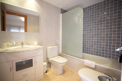 een badkamer met een wit toilet, een wastafel en een spiegel bij MontePerdido in Aínsa