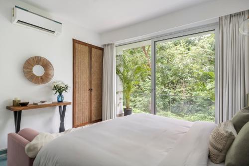 a bedroom with a white bed and a large window at La Olalian 2 & 3 BHK Designer Villas Near Anjuna Beach with Private Pool & Sun Deck & Garden in Anjuna