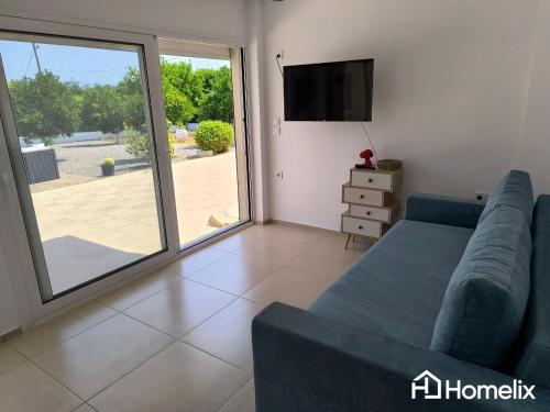 a living room with a blue couch and a sliding glass door at Venecia of Mani - Relax in a spa pool in Loukísia