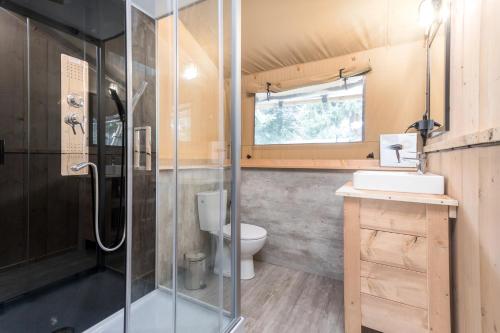a bathroom with a glass shower and a toilet at Landal Glamping Neufchâteau in Neufchâteau