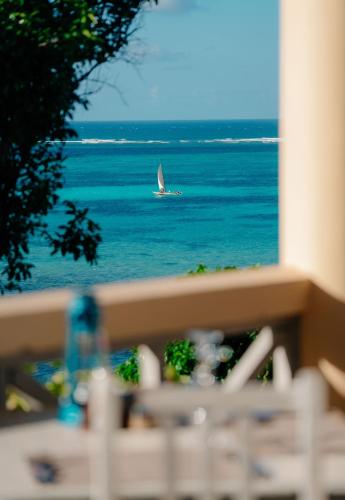 a sailboat on the water with a boat in the ocean at Pearl Beach by Sansi in Michamvi