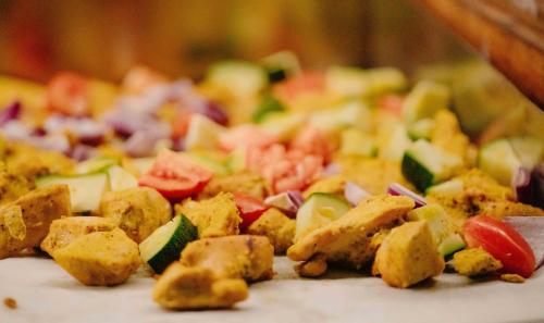 a close up of a pizza with vegetables on it at Pearl Beach by Sansi in Michamvi