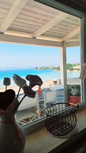 a vase with flowers on a balcony with a view of the beach at Cottage DeLuxe in Golfo Aranci