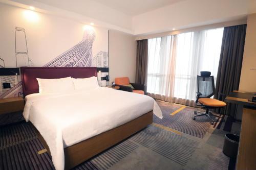 a hotel room with a large bed and a desk at Hampton by Hilton Guangzhou Zhujiang New Town - Free Shuttle Bus to Canton Fair in Guangzhou