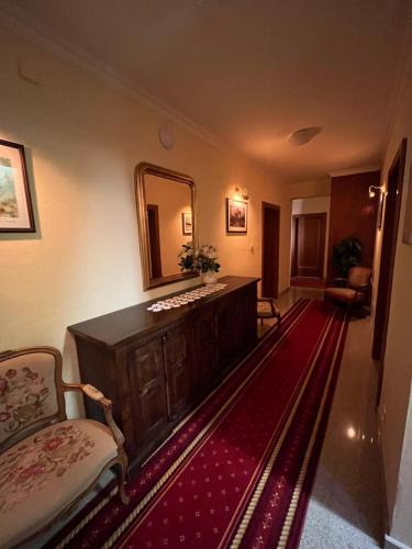 a bathroom with a vanity and a mirror and a red rug at Penzión Kastiel Hanus in Spišské Hanušovce