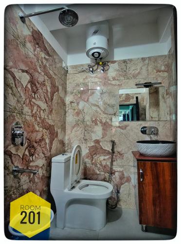 a bathroom with a white toilet and a stone wall at Shri Ganga View Guest House in Rishīkesh