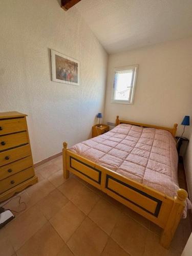 a bedroom with a bed and a dresser and a window at Appartement - 4 chambres - piscine collective- place de parking privée (garage) in Saintes-Maries-de-la-Mer