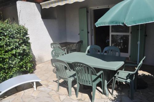 a table and chairs and an umbrella on a patio at Appartement - 4 chambres - piscine collective- place de parking privée (garage) in Saintes-Maries-de-la-Mer
