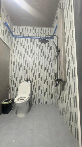 a bathroom with a toilet and a tiled wall at sunnyhome 2 wide spaces in Ấp Ðại Tài (2)
