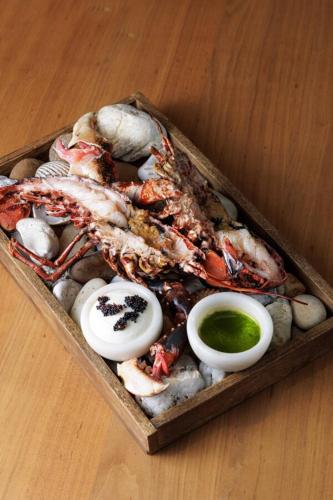 a tray of food with crabs and sauce on a table at Logis Hôtel & Restaurant LES MOUETTES - Larmor Plage, Proche de LORIENT in Larmor-Plage