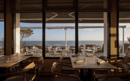 a restaurant with tables and chairs and a view of the ocean at Logis Hôtel & Restaurant LES MOUETTES - Larmor Plage, Proche de LORIENT in Larmor-Plage