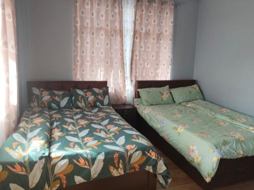 a bedroom with two beds and a window with curtains at Lake View Homestay in Mirik