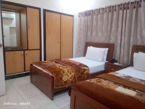 a hotel room with two beds and wooden cabinets at Stay Inn Guest House in Karachi