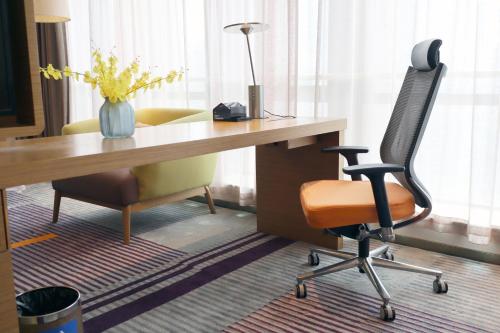 an office with a desk with a chair and a vase of flowers at Hampton by Hilton Guangzhou Zhujiang New Town - Free Shuttle Bus to Canton Fair in Guangzhou