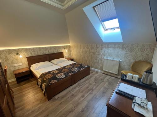a bedroom with a bed and a desk and a window at Penzión Kastiel Hanus in Spišské Hanušovce