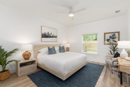 Habitación blanca con cama, mesa y escritorio. en Sun Seekers Beach House- Steps from Butler Beach, en St. Augustine