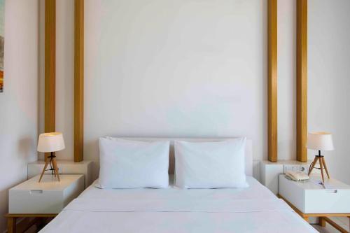 a white bed with two nightstands and two lamps at Labranda TMT Bodrum in Bodrum City