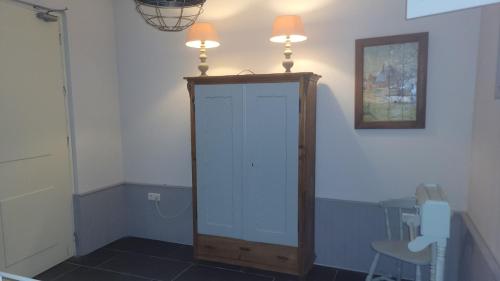 a room with a white cabinet with two lights on top at B&B Van Hunebed Naar Jullie Bed in Schoonoord