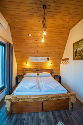 a large bed in a room with a wooden ceiling at Complex A Toplita in Topliţa
