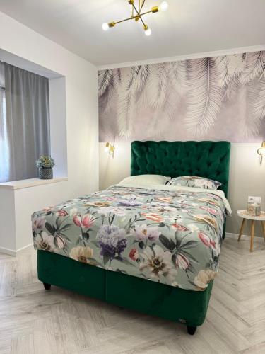 1 Schlafzimmer mit einem grünen Bett und einer Blumenbettdecke in der Unterkunft Apartament Victoria in Tîrnăveni