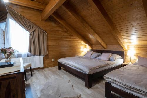 a bedroom with two beds in a wooden room at Chata Sidorka in Oravský Podzámok