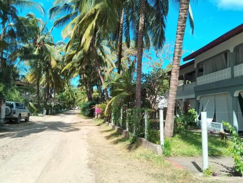 a dirt road with palm trees next to a building at Marially Luxury Bed and Breakfast in Malindi
