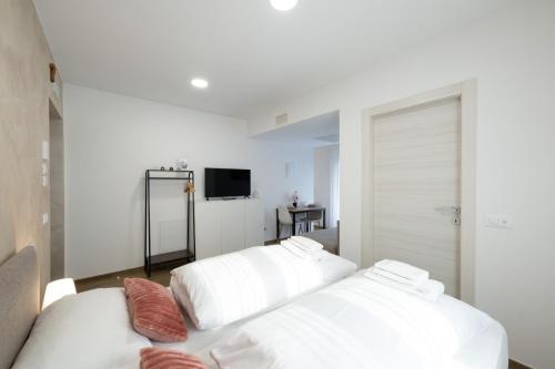 two white beds in a room with a television at Villa Betty Apartments in Arco