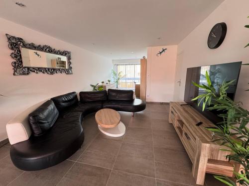 a living room with a black leather couch and a tv at Le Maxime 7 in Sainte-Maxime