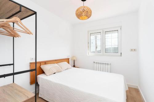 a white bedroom with a bed and a window at Maravillosa casa con jardín cerca de playa en centro de Asturias in Llodares