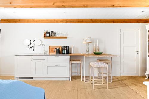 a kitchen with white cabinets and a counter with stools at Solbjerggaard Bed & Breakfast in Fåborg
