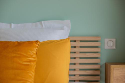 a bed with a yellow pillow in a bedroom at La Longere - Calme Neuf 15 min Amiens in Vers-sur-Celle