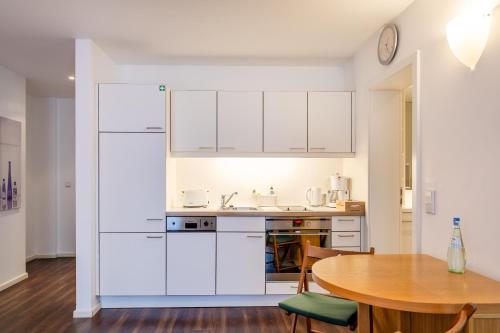 a kitchen with white cabinets and a wooden table at Hotel Alma Am Anger in Erfurt