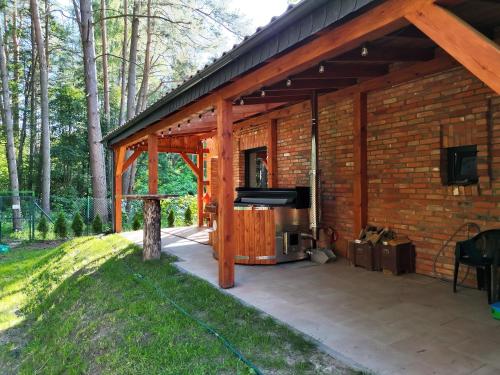 a screened in patio with a television and a brick building at Ceglany Domek z jacuzzi, nad jeziorem, przy lesie in Tomaszkowo
