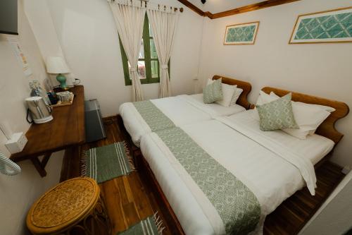 a bedroom with two beds and a table with a telephone at Barn Laos Luangprabang Heritage in Luang Prabang