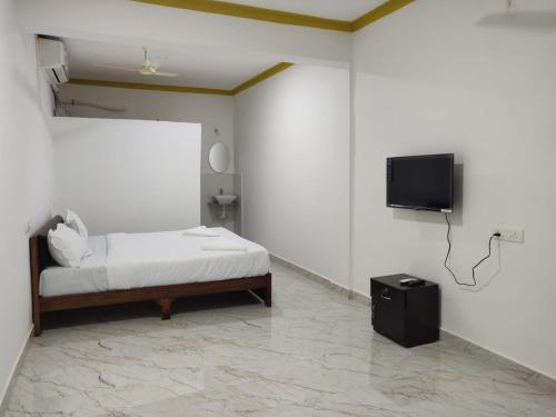 a bedroom with a bed and a flat screen tv at cbc joy resort in Calangute