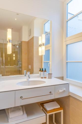a white bathroom with a sink and a window at Hotel Alma Am Anger in Erfurt