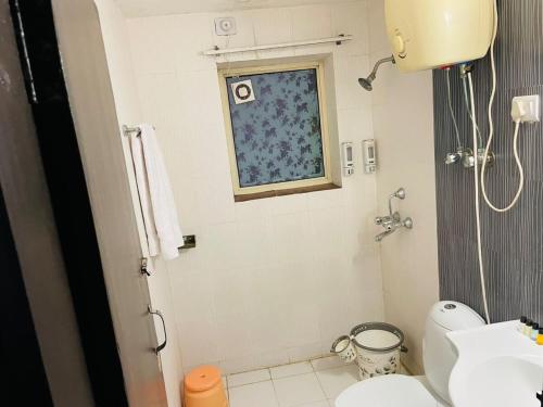 a bathroom with a sink and a toilet and a window at Luxury & Peaceful stay in Omaxe in Vrindāvan