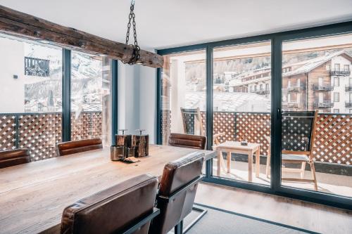 a dining room with a table and chairs and large windows at Navigare Resorts in Saas-Fee