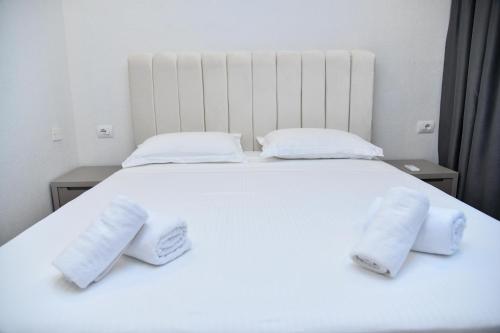 a white bed with two white towels on it at Amber Hotel Albania in Spille
