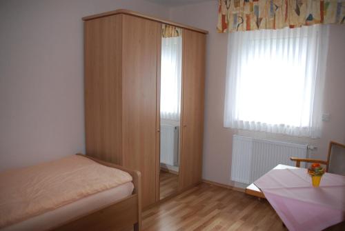 a bedroom with a wooden cabinet and a bed and a window at Gästehaus Stillecke in Erwitte