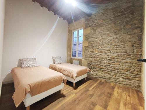 une chambre avec deux lits et un mur en pierre dans l'établissement L'ARCADIA 4 lits Climatisé Jeu d'Arcade centre historique Nîmes, à Nîmes