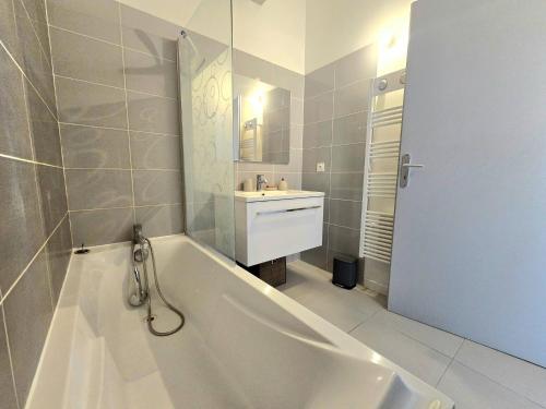 une salle de bain blanche avec une baignoire et un lavabo dans l'établissement Cozy 2 bedroom house with Garden & Parking, à Nîmes