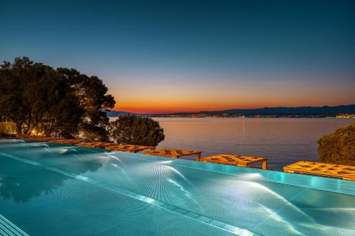 a swimming pool with a view of the water at Spa & Wellness Hotel Pinia in Malinska