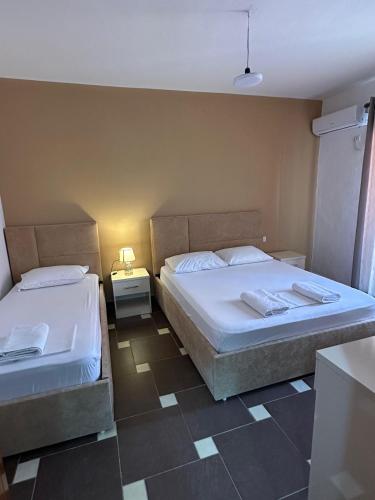 a bedroom with two beds and a night stand with a lamp at Balkan Apartaments in Shëngjin