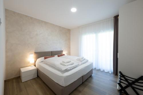 a bedroom with a white bed and a window at Villa Betty Apartments in Arco