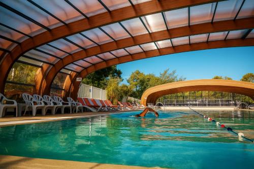 une personne se baignant dans une piscine sous un pont dans l'établissement Cozy-House tout confort camping 4 étoiles, à Lège-Cap-Ferret