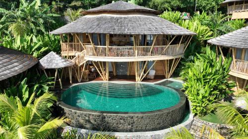 an exotic resort with a swimming pool and a building at Villas Bukit Lipah in Amed