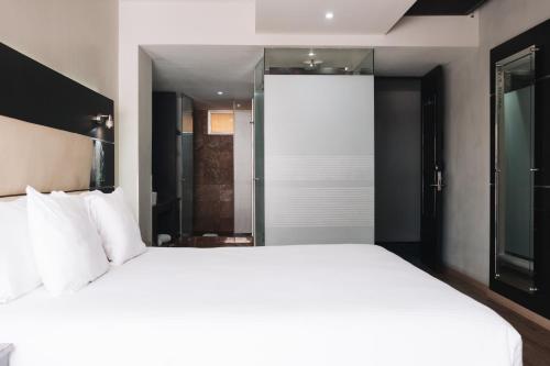 a bedroom with a large white bed and a glass door at Exe Cities Reforma in Mexico City
